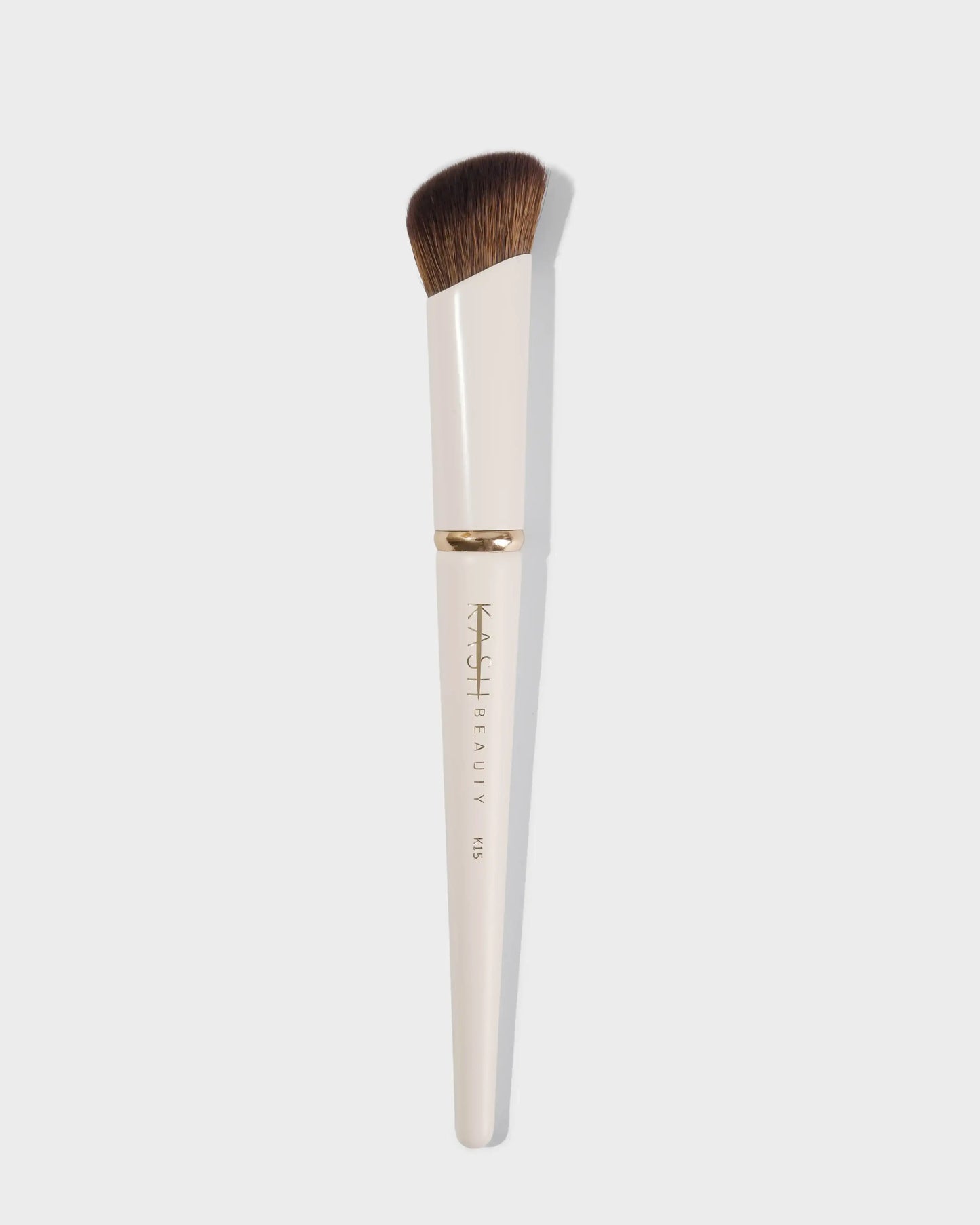Angled concealer brush with cream handle and soft brown bristles on white background