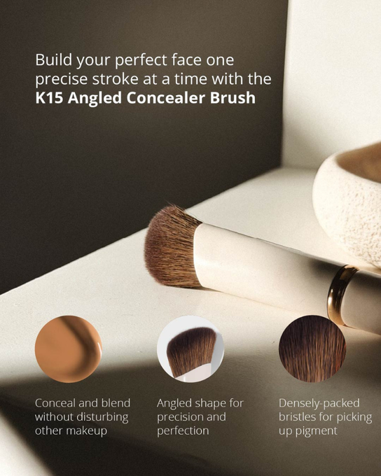 Angled concealer brush with cream handle and soft brown bristles on white background