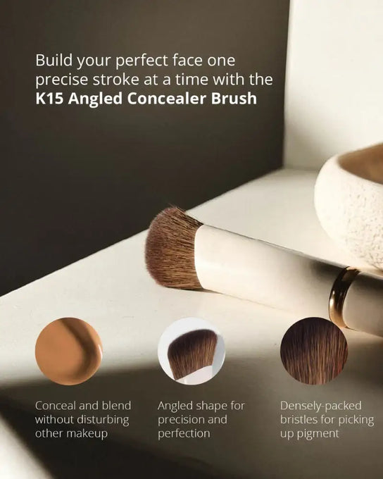 Angled concealer brush with cream handle and soft brown bristles on white background
