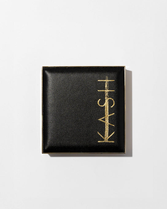 Pressed translucent setting powder in a black and gold compact with embossed K on powder