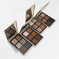 Three open eyeshadow palettes with gold-toned cases, arranged diagonally on a clean white background. Each palette contains multiple square pans of neutral and warm-toned makeup, including browns, beiges, tans, and soft pinks.