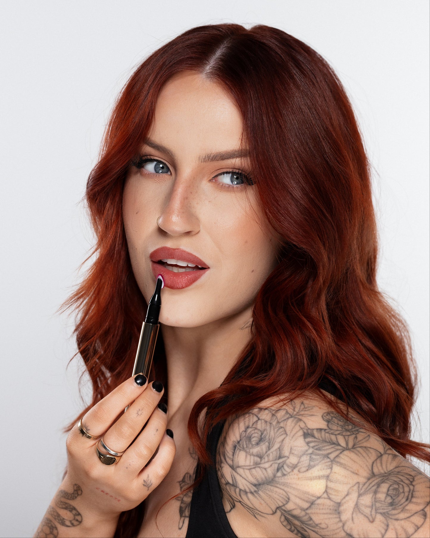 Woman with red hair holding a makeup brush against a white background