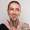 Woman holding five gold Kash Beauty Brow Pencils against a plain background