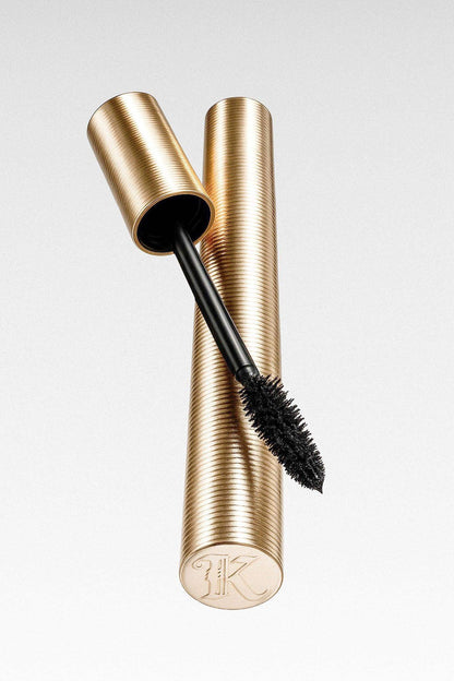 Gold mascara tube with textured finish and black mascara wand on white background