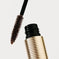 Close-up of brown mascara wand with textured gold tube on white background