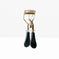 Gold eyelash curler with black handles on white background, professional beauty tool