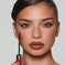 Woman with flawless makeup holding brown mascara wand, perfect brows and bold lips