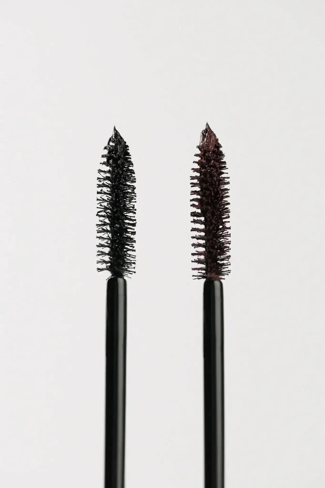 Two mascara wands with black and brown product on white background