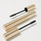 Two gold mascara tubes with textured lids and open wands on a light background