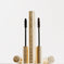 Two gold mascara tubes with textured cases and black and brown wands on white background
