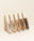 Five liquid concealers in different shades lined up on a beige background